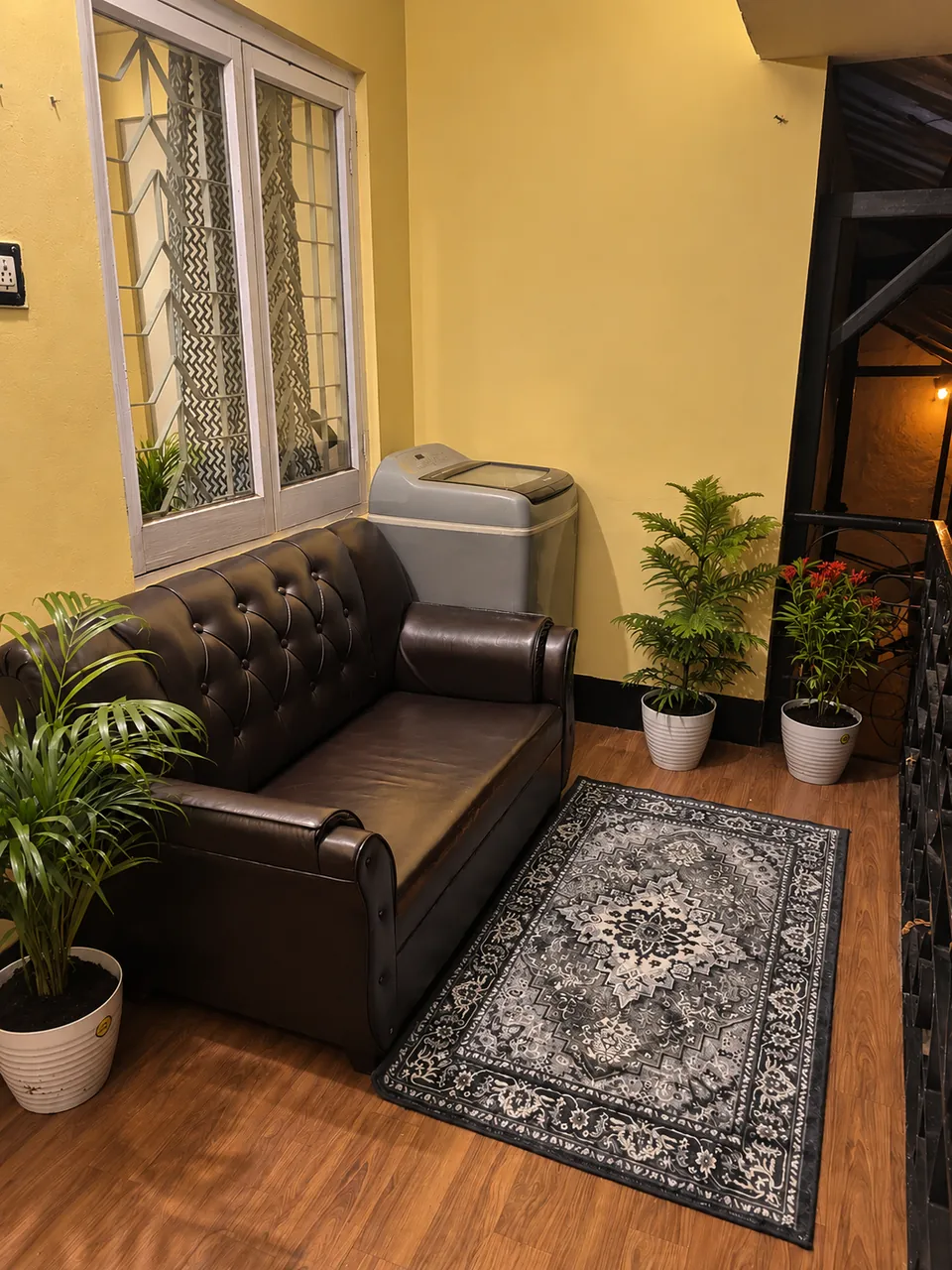 Balcony seating corner with a tufted leather sofa, a rug and potted plants
