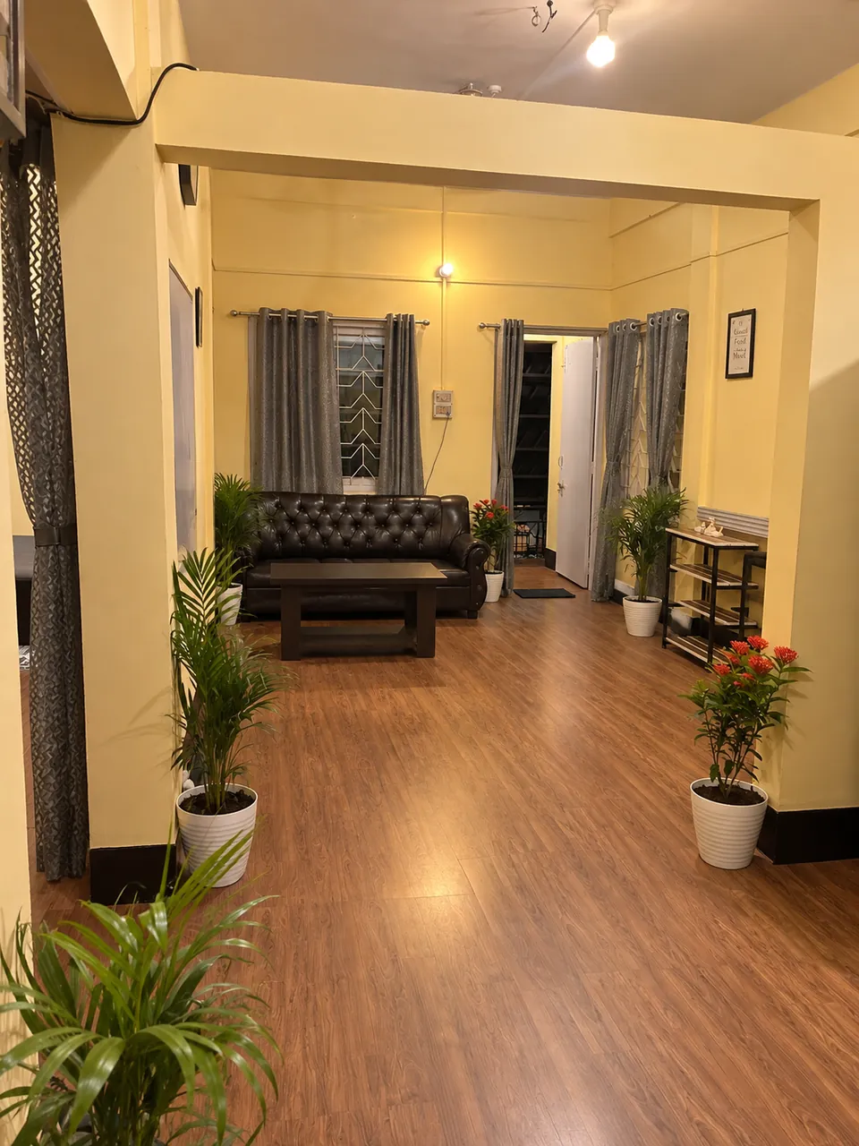 View down the hallway into the living room, with wood floors and grey curtains
