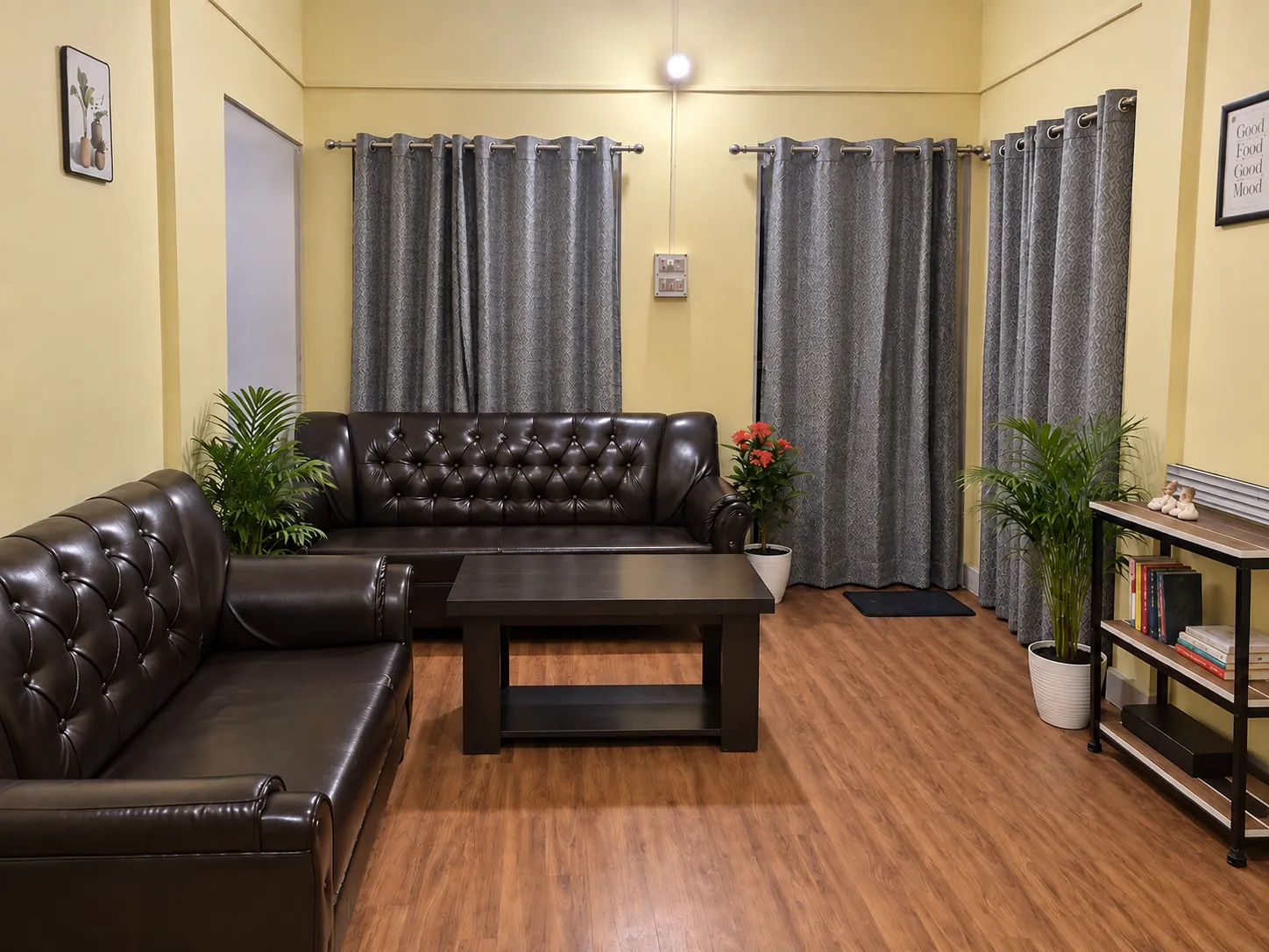 The living room at River Side: 2 tufted leather sofas, a coffee table, plants and a bookshelf