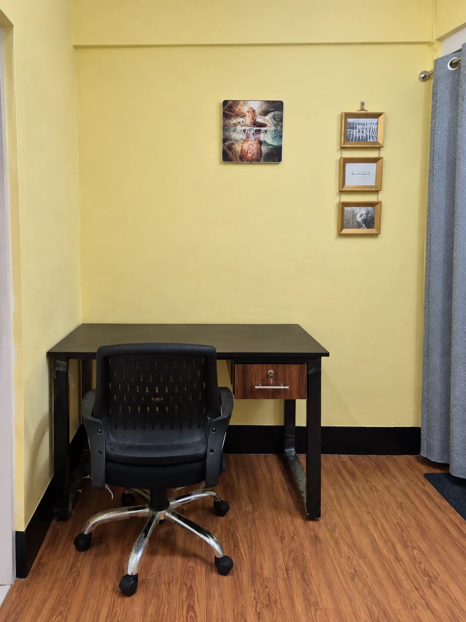 Work desk with a drawer, a mesh office chair and framed prints